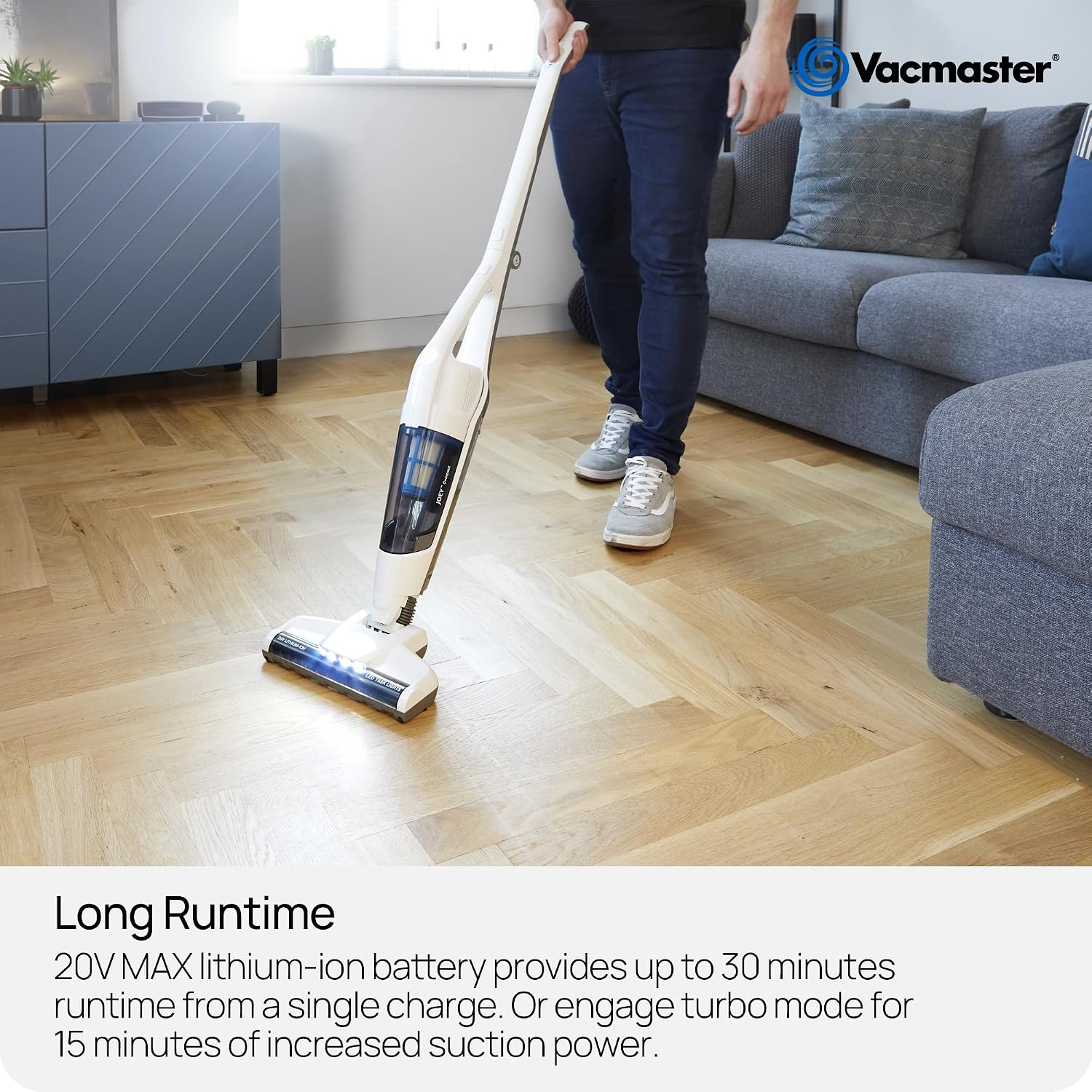 Eine Person benutzt einen weißen kabellosen Vacmaster-Staubsauger auf einem Holzboden in einem Wohnzimmer.