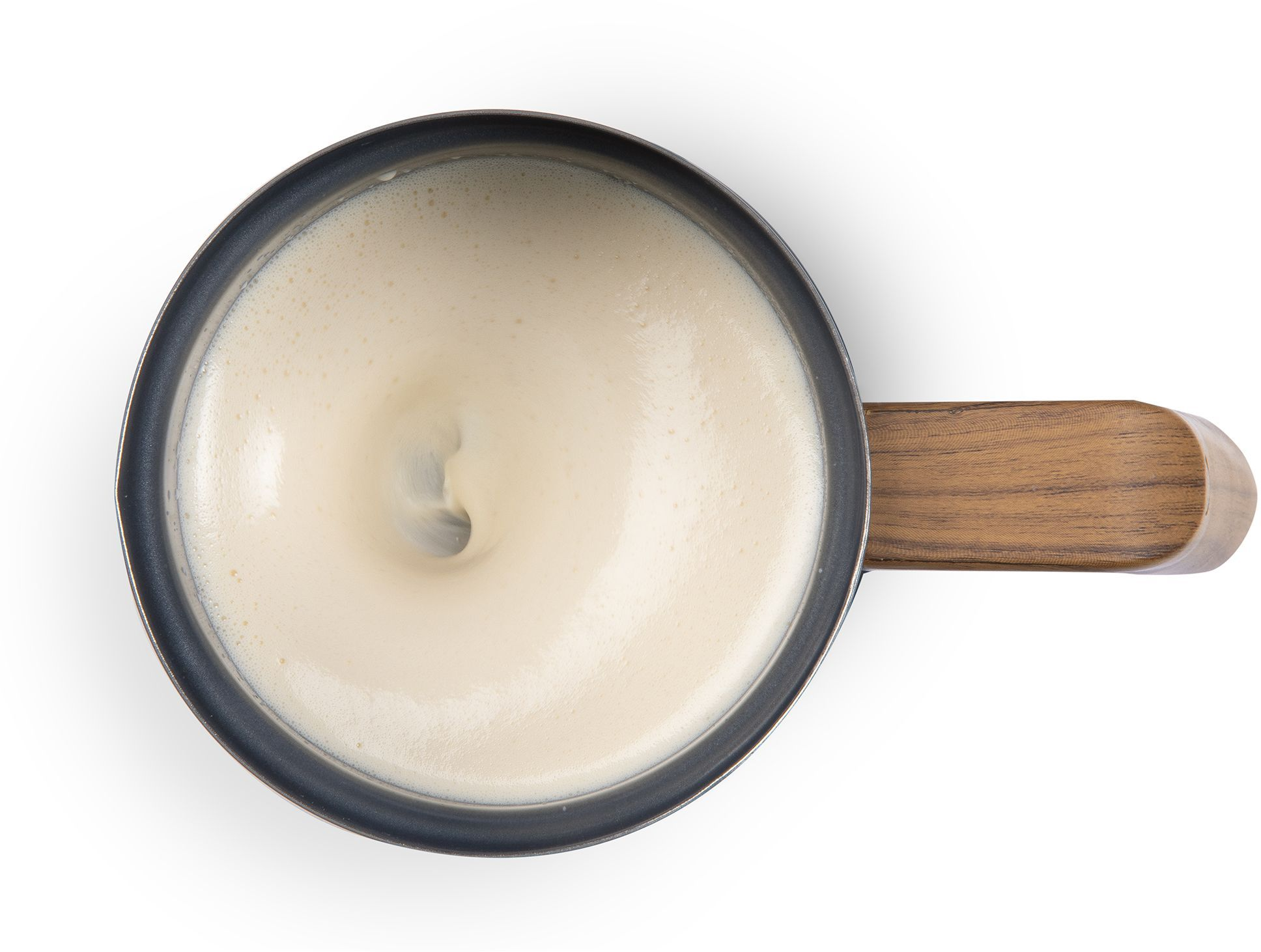 Top-Down-Ansicht eines schwarzen Topfes mit Holzgriff, gefüllt mit cremig aufgeschäumter Milch auf weißem Hintergrund.