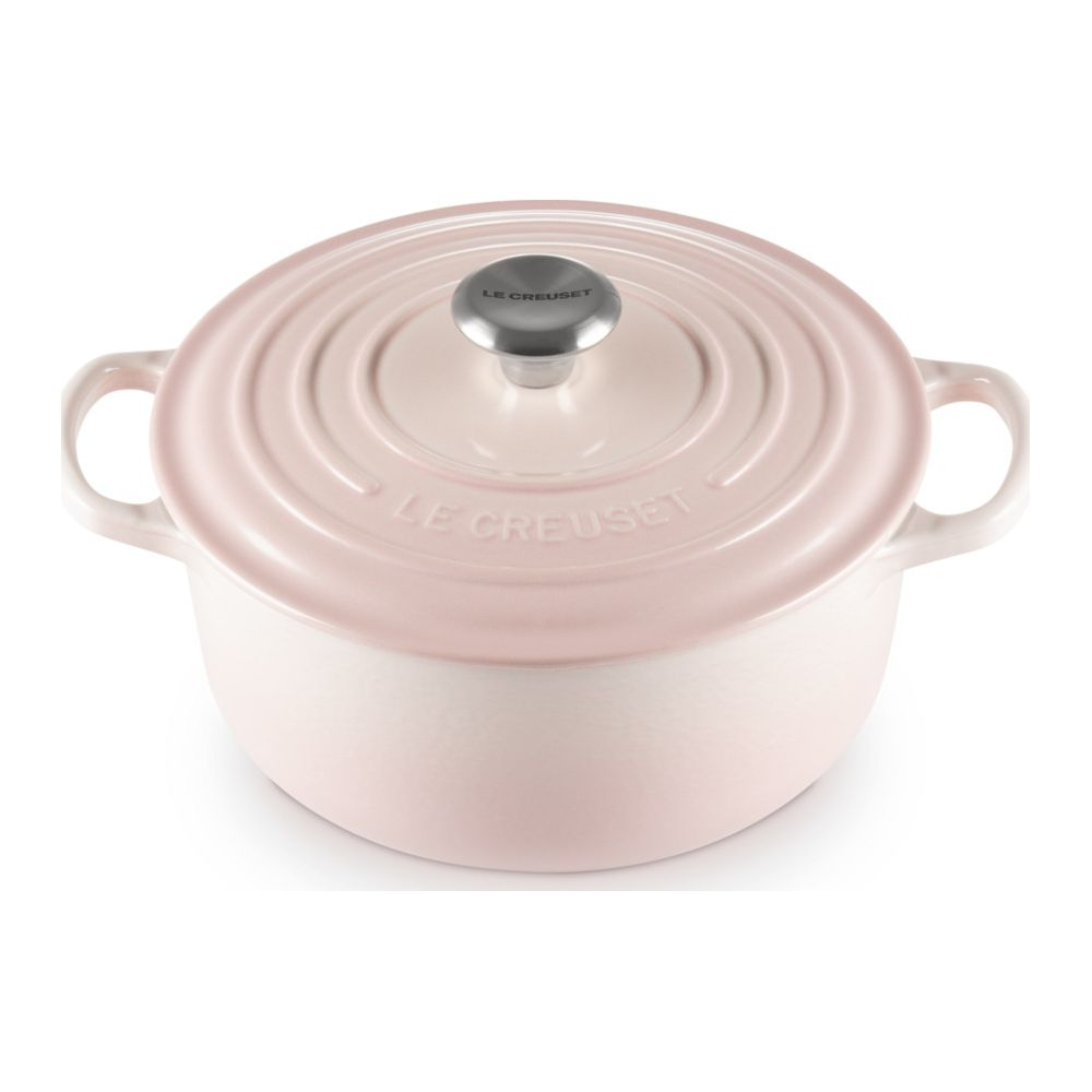 Une cocotte ronde en fonte rose Le Creuset avec couvercle sur fond blanc.