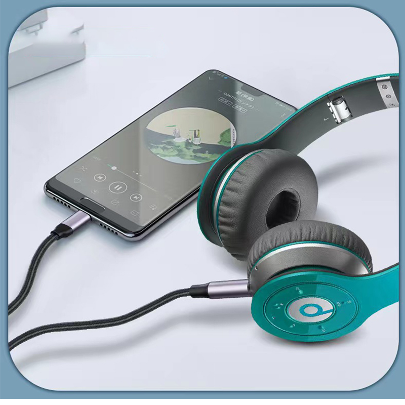 Grüne On-Ear-Kopfhörer sind per Kabel mit einem Smartphone verbunden, auf dem ein Musikplayer läuft.