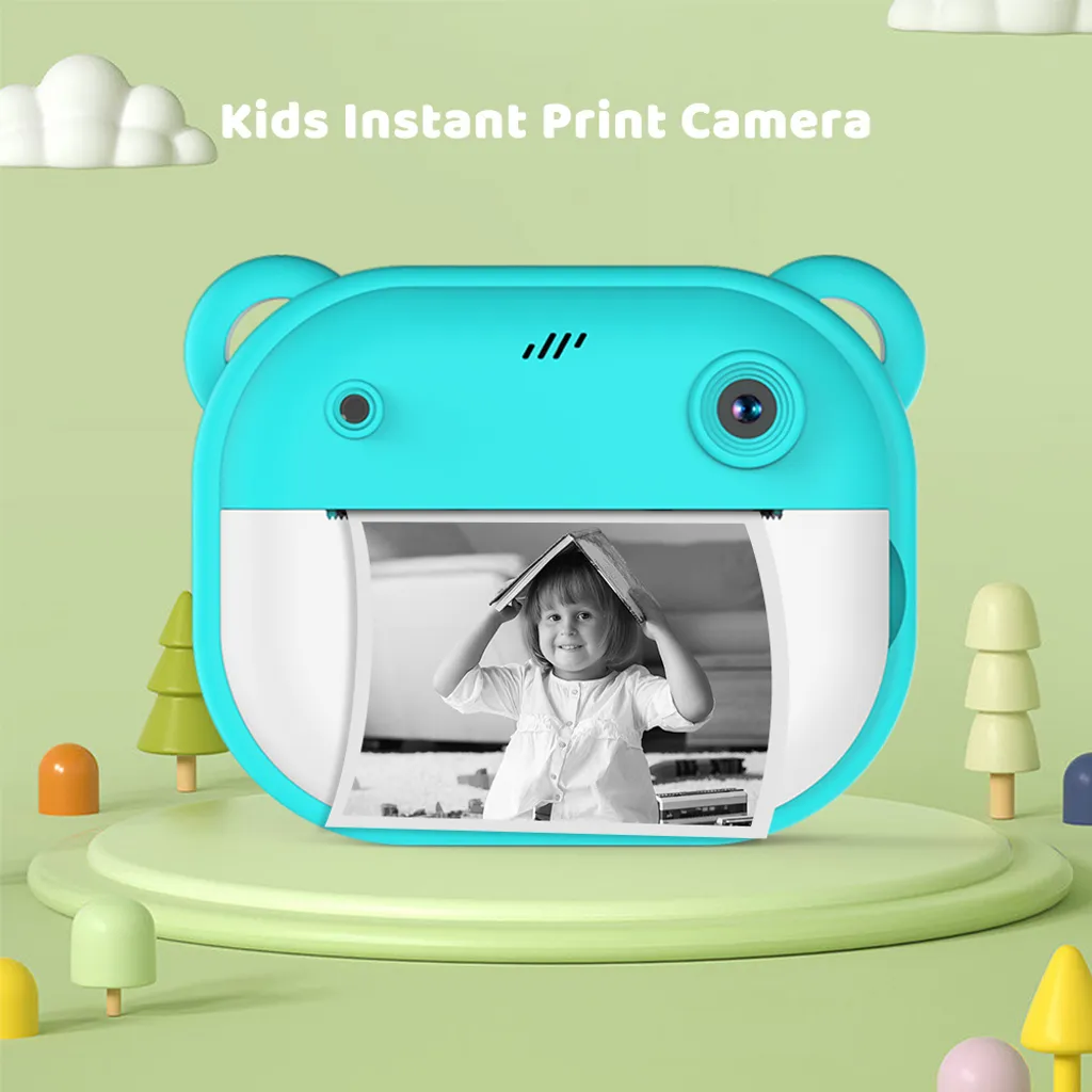 Blaue Kinder-Sofortbildkamera in Bärenform auf grünem Podest mit gedrucktem Foto eines Kindes.