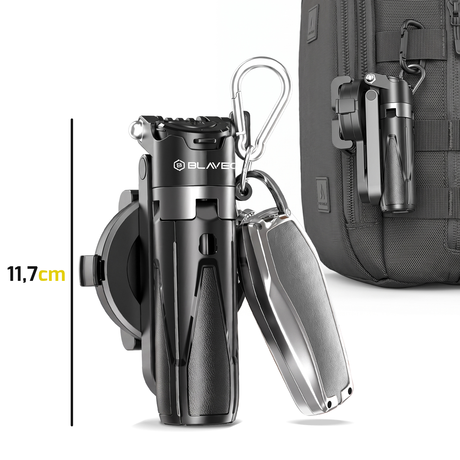 Schwarzes 11,7 cm Mini-Stativ mit Karabiner und Autoschlüssel, im Hintergrund ein Rucksack.