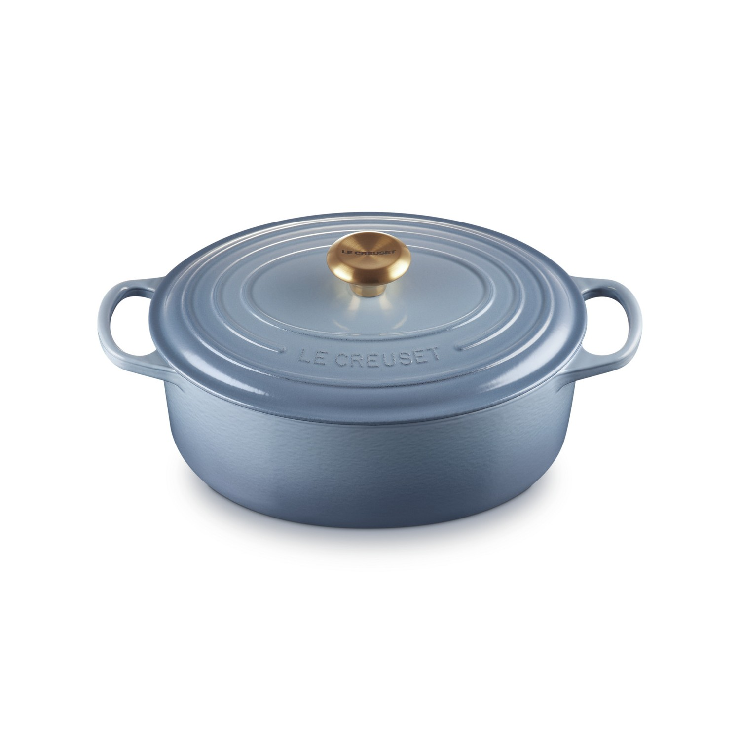 Une cocotte en fonte bleue Le Creuset avec un bouton doré sur fond blanc.