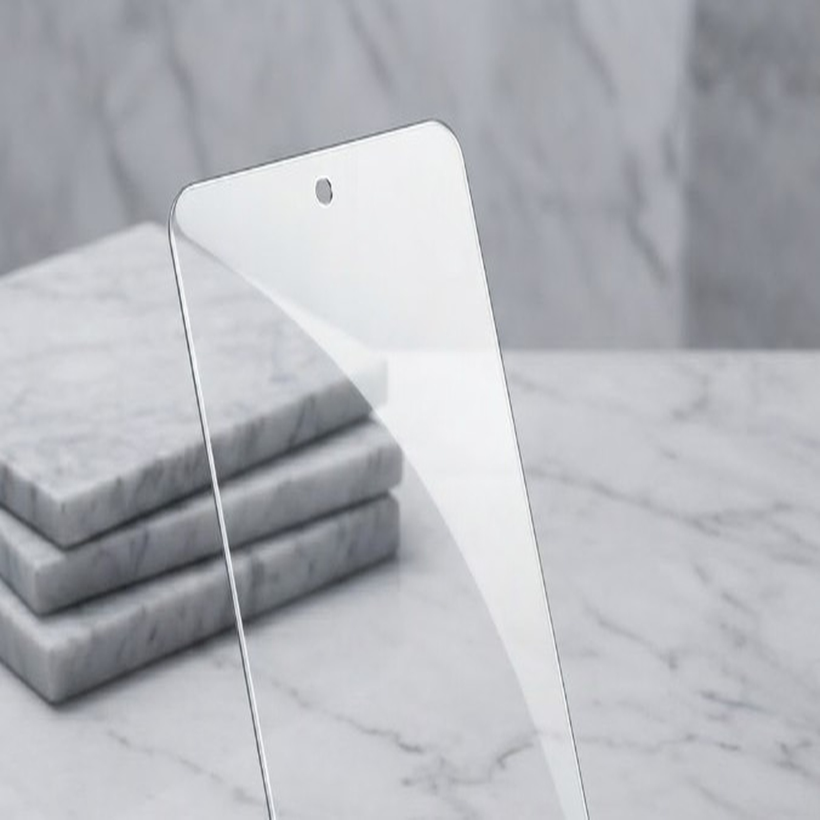 Un protector de pantalla transparente se encuentra sobre una superficie de mármol con azulejos apilados.