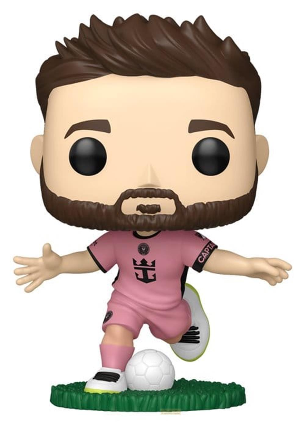 Una figura Funko Pop con camiseta rosa patea un balón de fútbol en césped verde.