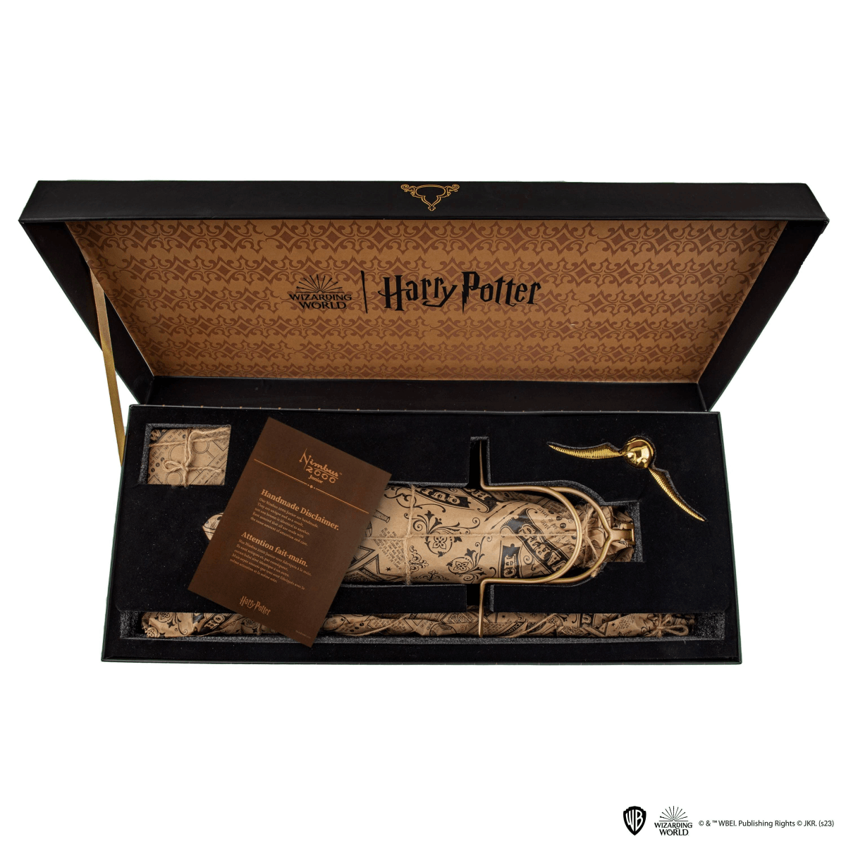 Une boîte Harry Potter ouverte contient une baguette emballée, un vif d'or et un document.