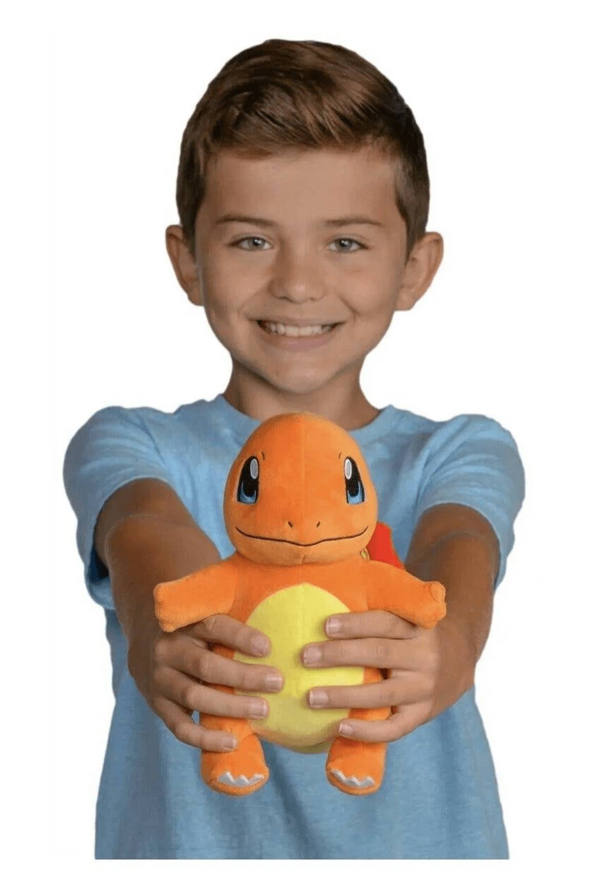 Un garçon souriant vêtu d'un t-shirt bleu tient une peluche orange de Salamèche vers la caméra.