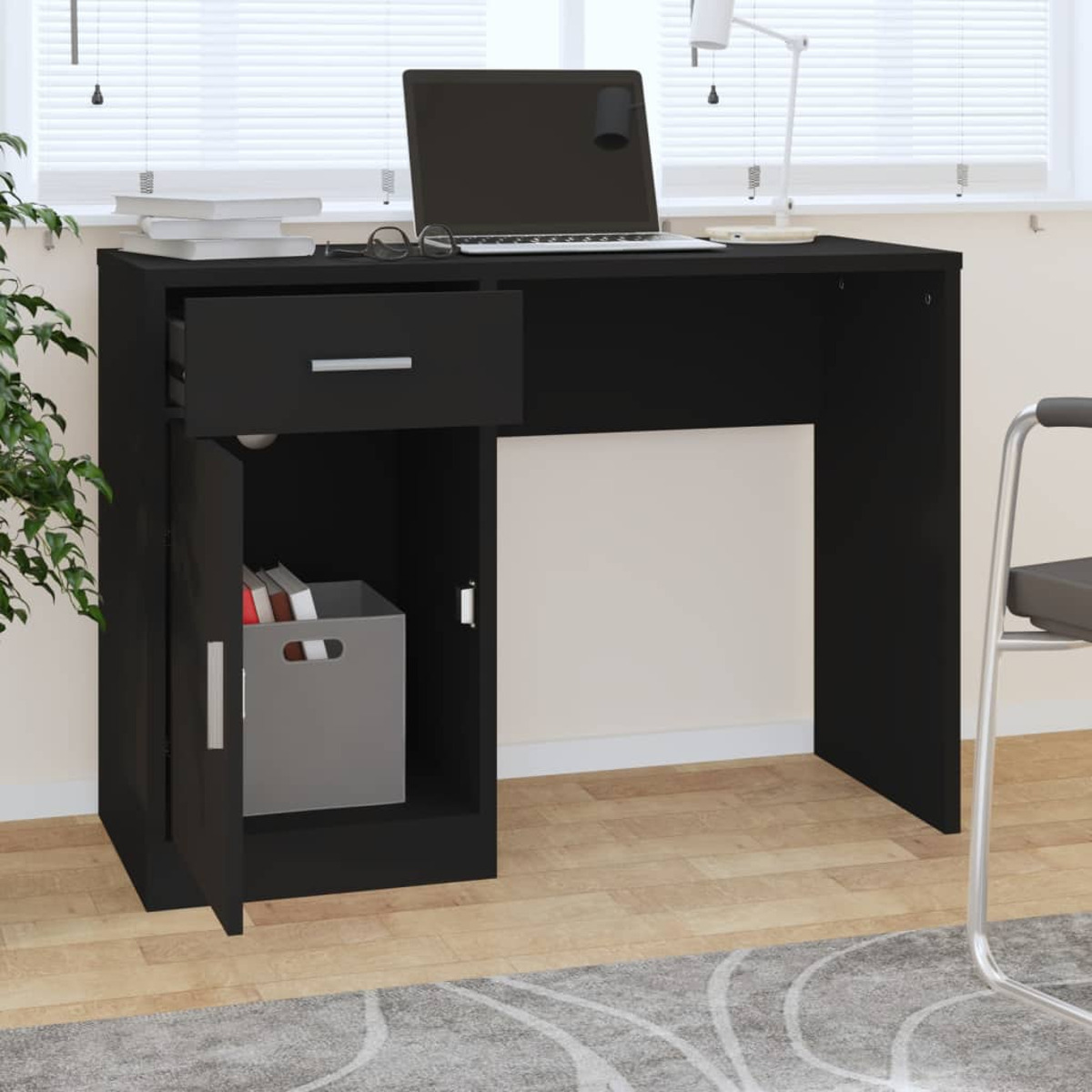 Ein schwarzer Schreibtisch mit offener Schublade, einem Schrank mit Kiste und einem Laptop darauf im Büro.