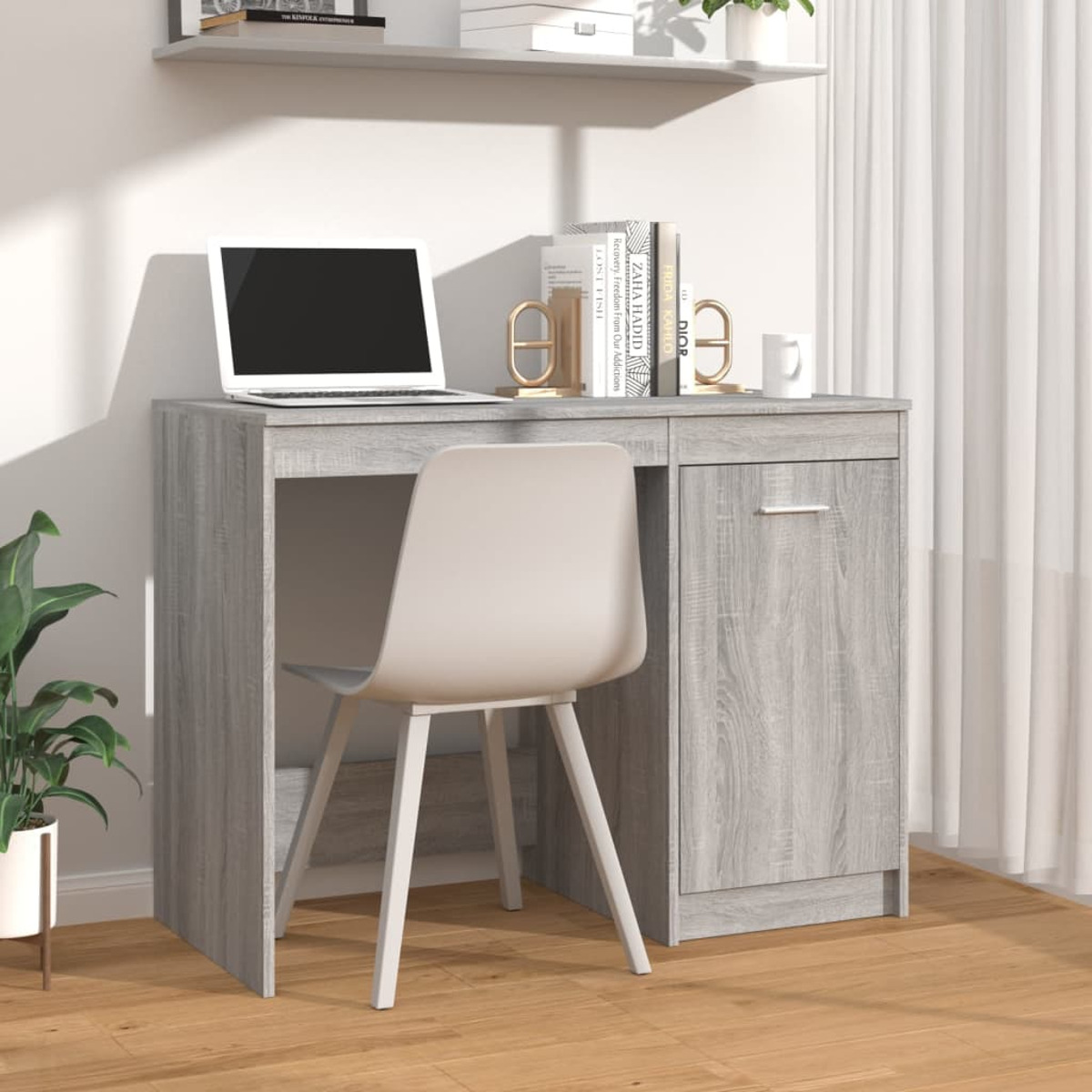 Grauer Schreibtisch mit Laptop, Stuhl, Büchern und Regal in hellem Raum.