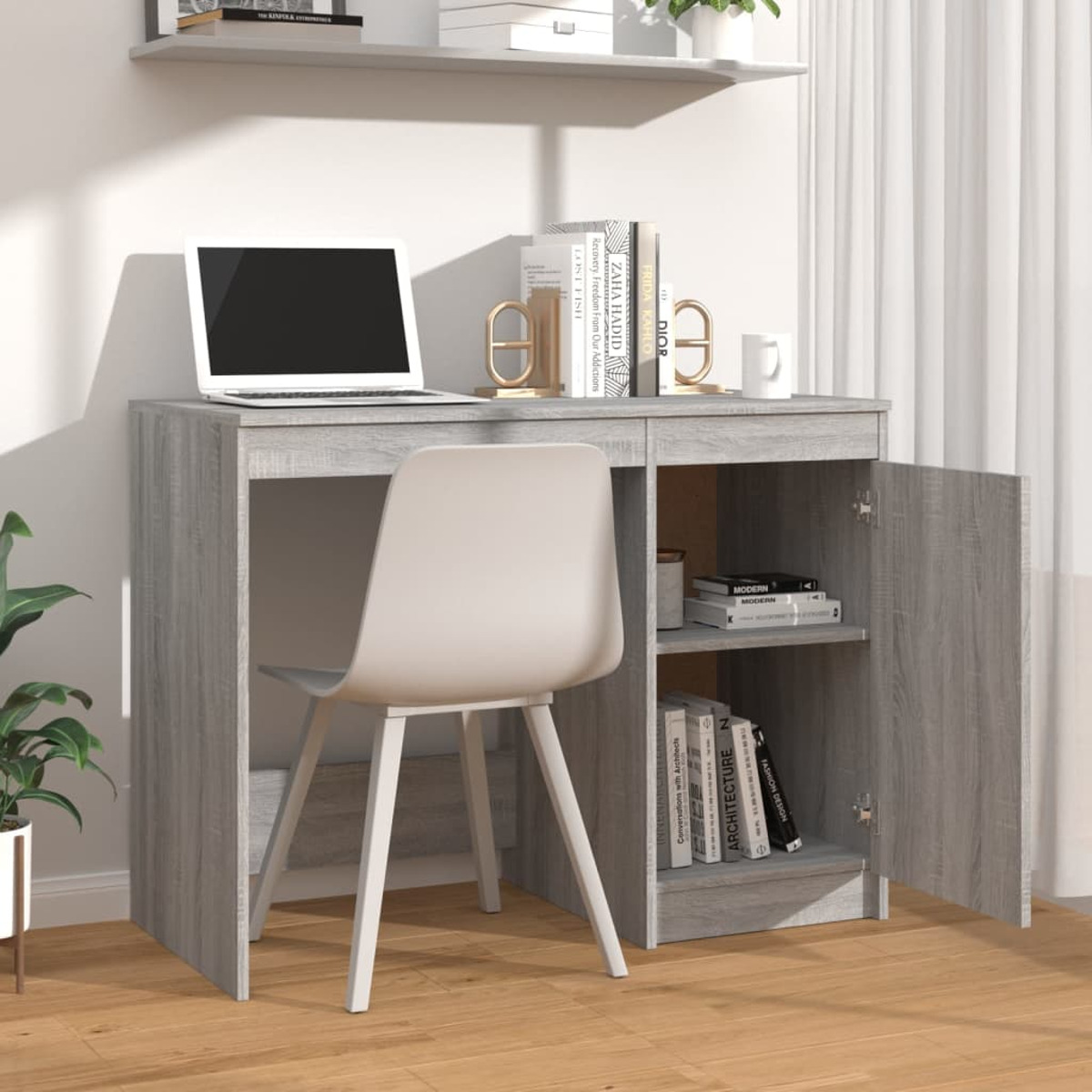 Ein grauer Schreibtisch mit Laptop, Büchern und weißem Stuhl.