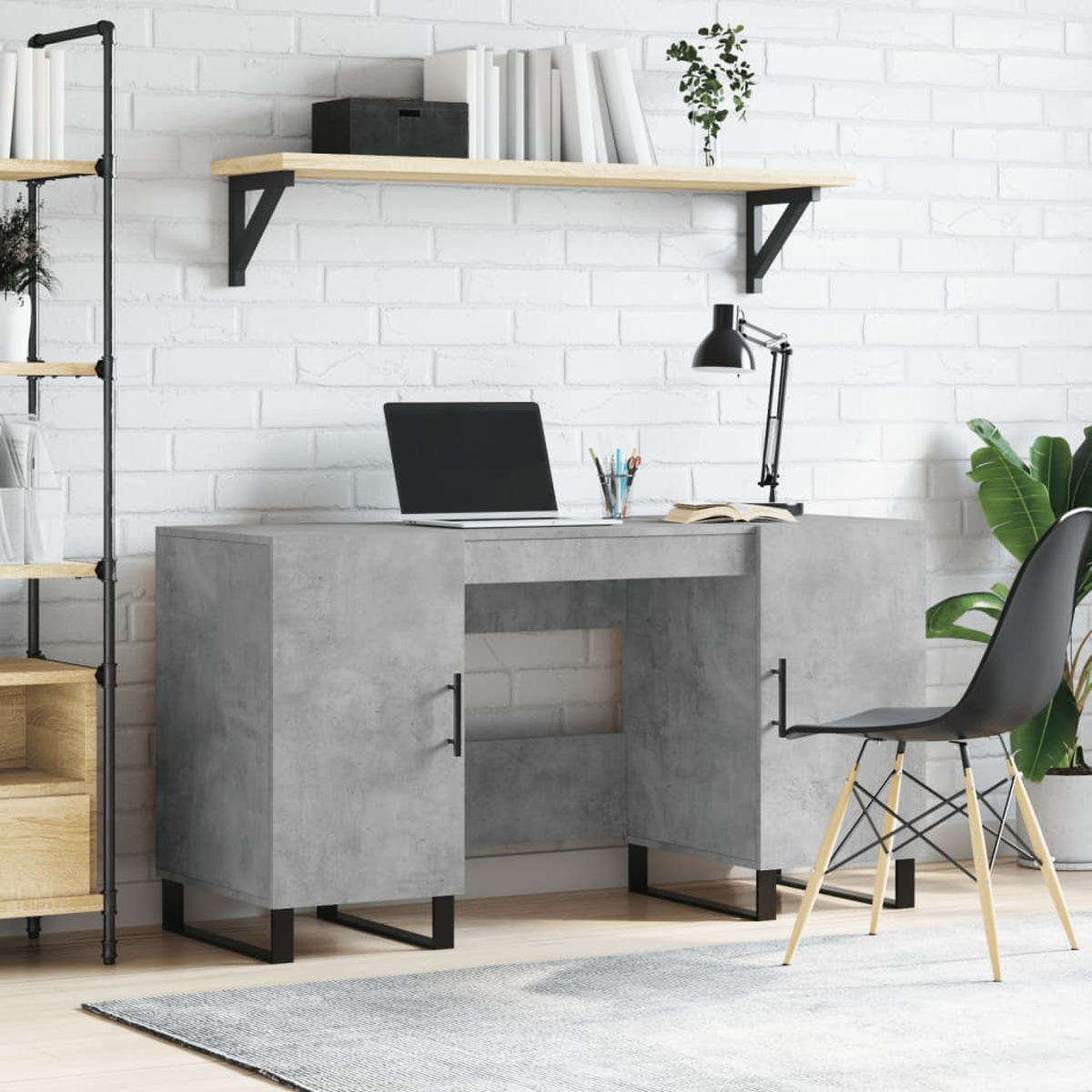 Ein grauer Betonschreibtisch mit Laptop, Lampe und schwarzem Stuhl vor einer weißen Backsteinwand.
