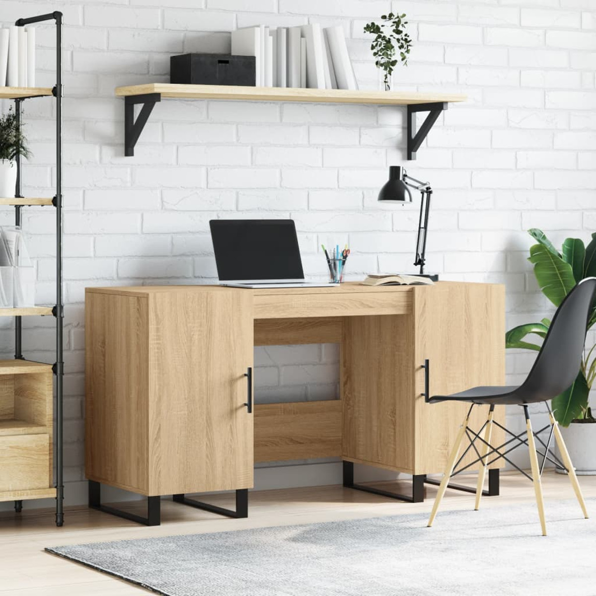 Holzschreibtisch mit Laptop und Lampe vor einer weißen Backsteinwand, dazu ein schwarzer Stuhl und ein Wandregal.