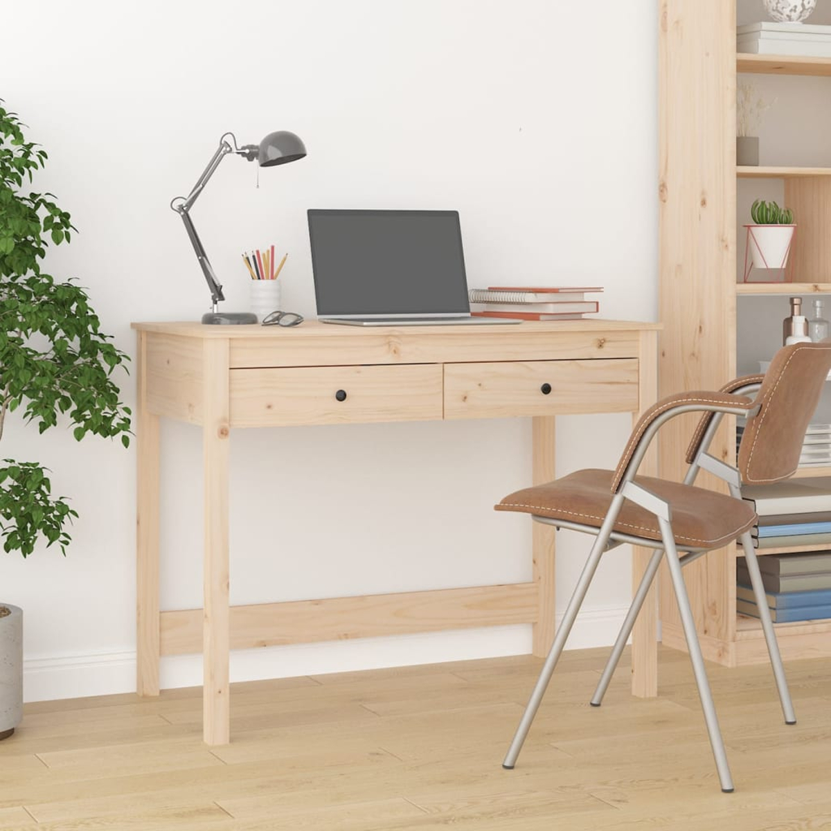 Ein Holztisch mit Laptop, Lampe, Büchern und Brille, dazu ein brauner Stuhl und ein Bücherregal.
