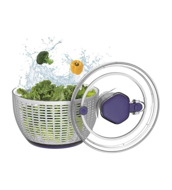 Marul, brokoli ve biberle dolu bir salata kurutucusu yukarı doğru su sıçratıyor, yanında kapağı var.