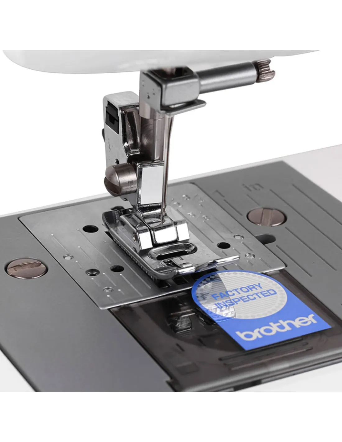 Primer plano del prensatelas plateado y la placa de aguja de una máquina de coser.