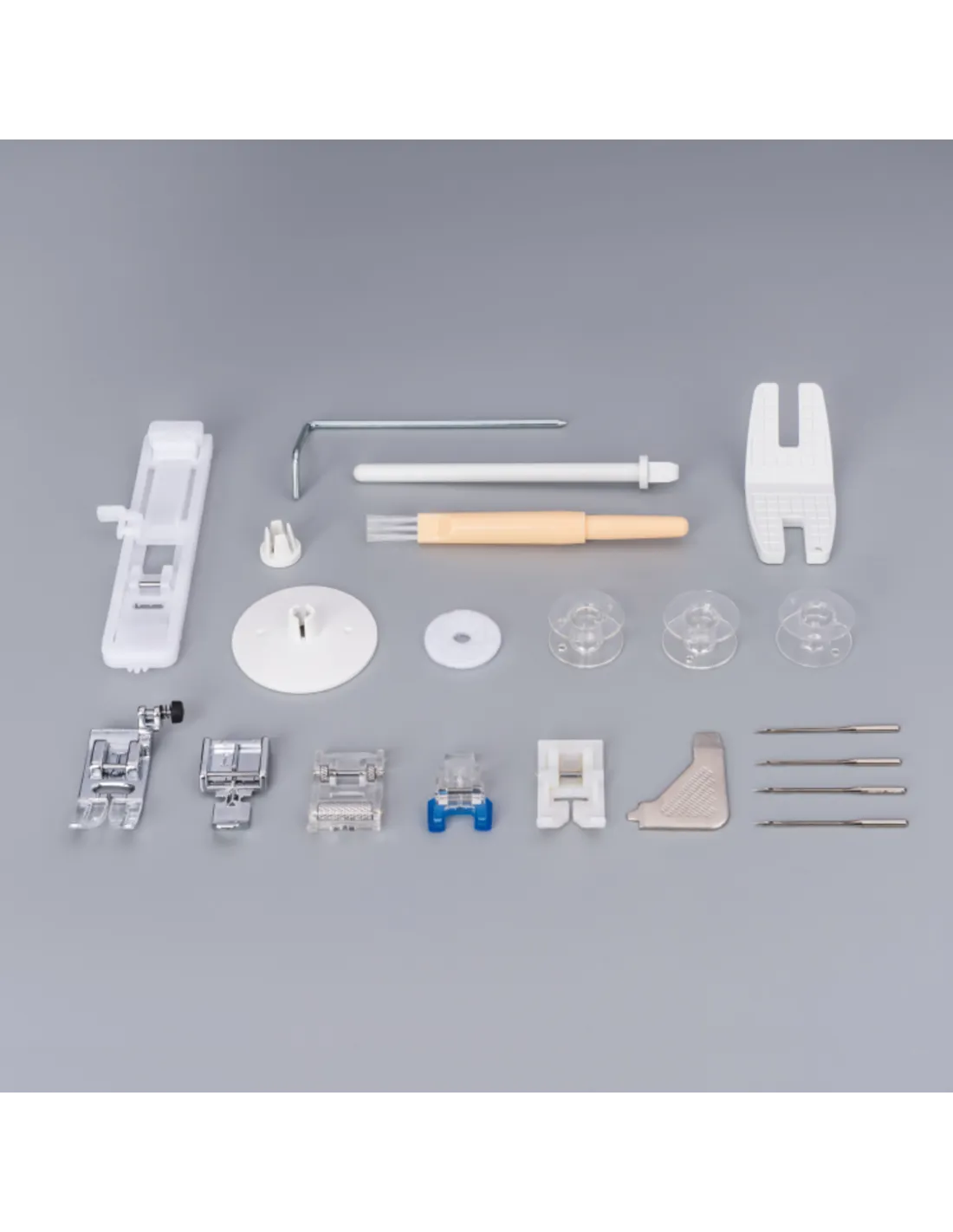 Various sewing machine parts and accessories like feet, bobbins, and needles are arranged on a grey surface.