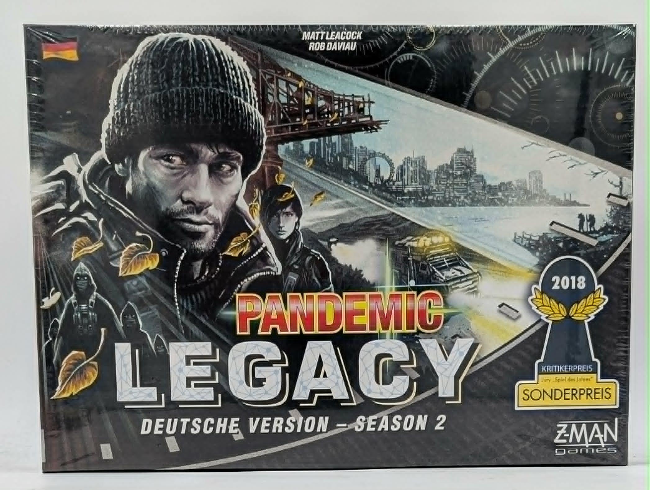 Brettspiel-Schachtel Pandemic Legacy Season 2 mit Charakteren vor einer zerstörten Stadt und Brücke.