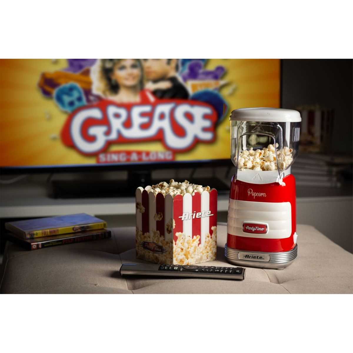 Oturma odasında kırmızı patlamış mısır makinesi, kutusu ve Grease ekranı.
