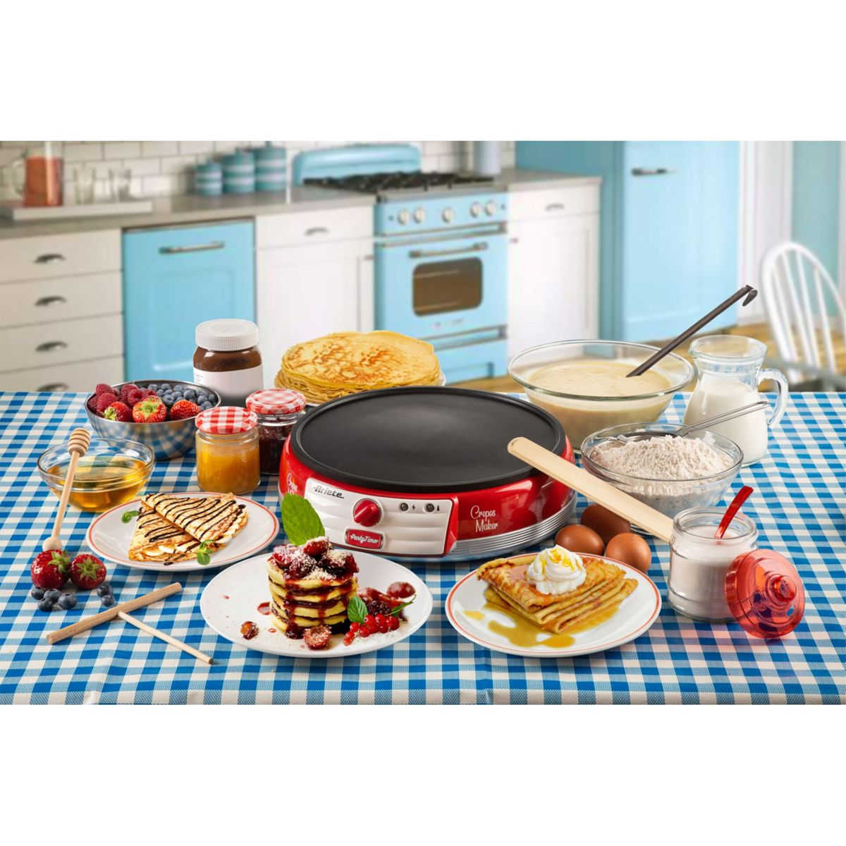 Un tavolo con crepiera, pastella, pancake, frutti di bosco, sciroppo e ingredienti in cucina.