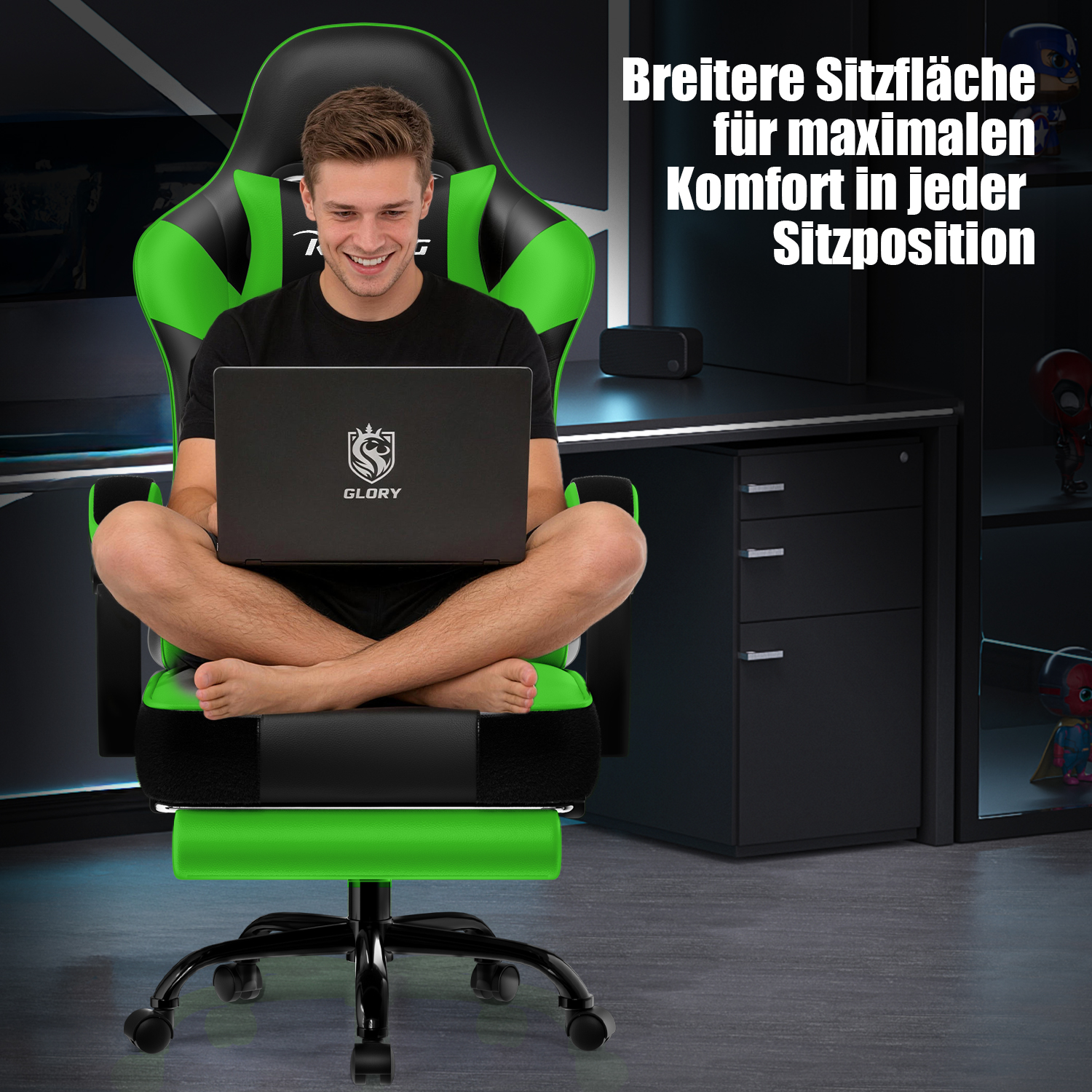Ein Mann sitzt mit gekreuzten Beinen auf einem breiten, schwarz-grünen Gaming-Stuhl und benutzt einen Laptop.