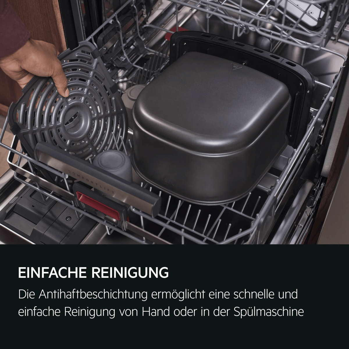 Hand legt ein schwarzes Airfryer-Teil in die geöffnete Spülmaschine.