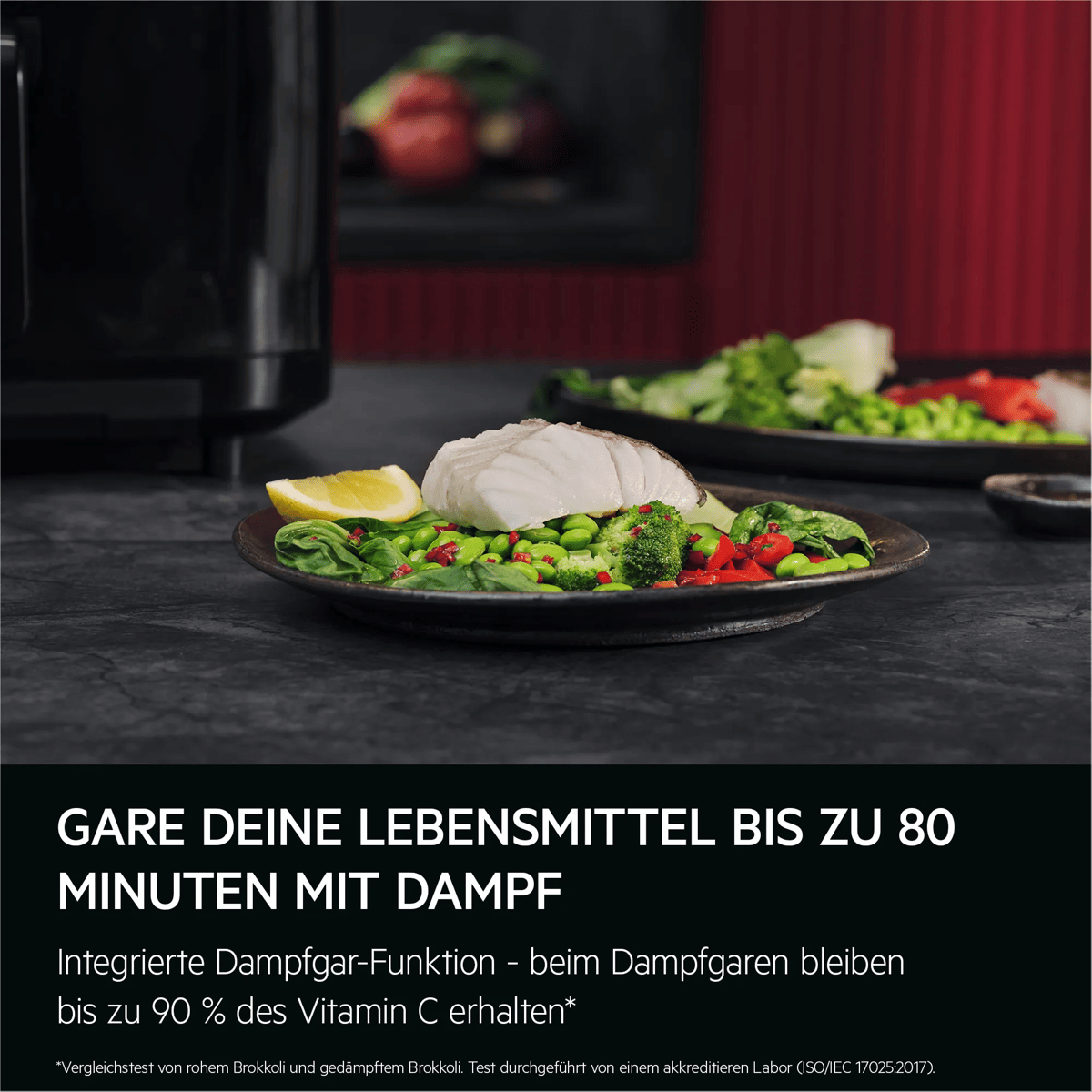 Ein Teller mit gedämpftem Fisch, Gemüse und Zitrone auf einer dunklen Arbeitsfläche.