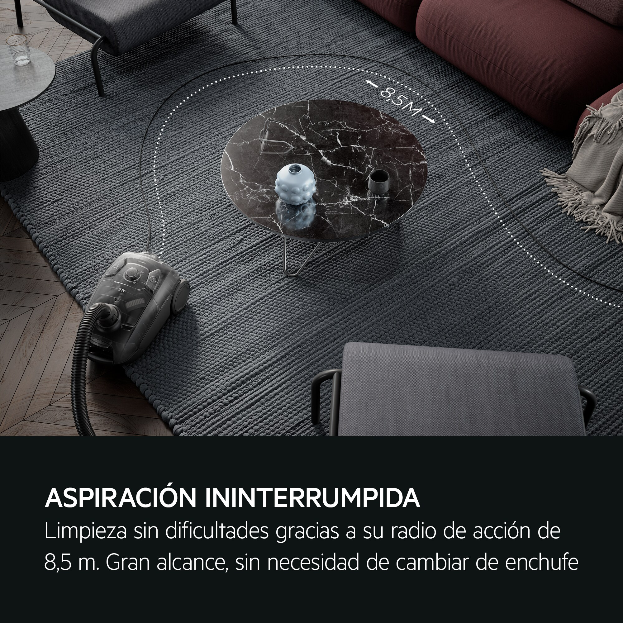 Una aspiradora gris sobre una alfombra junto a una mesa de centro redonda de mármol.