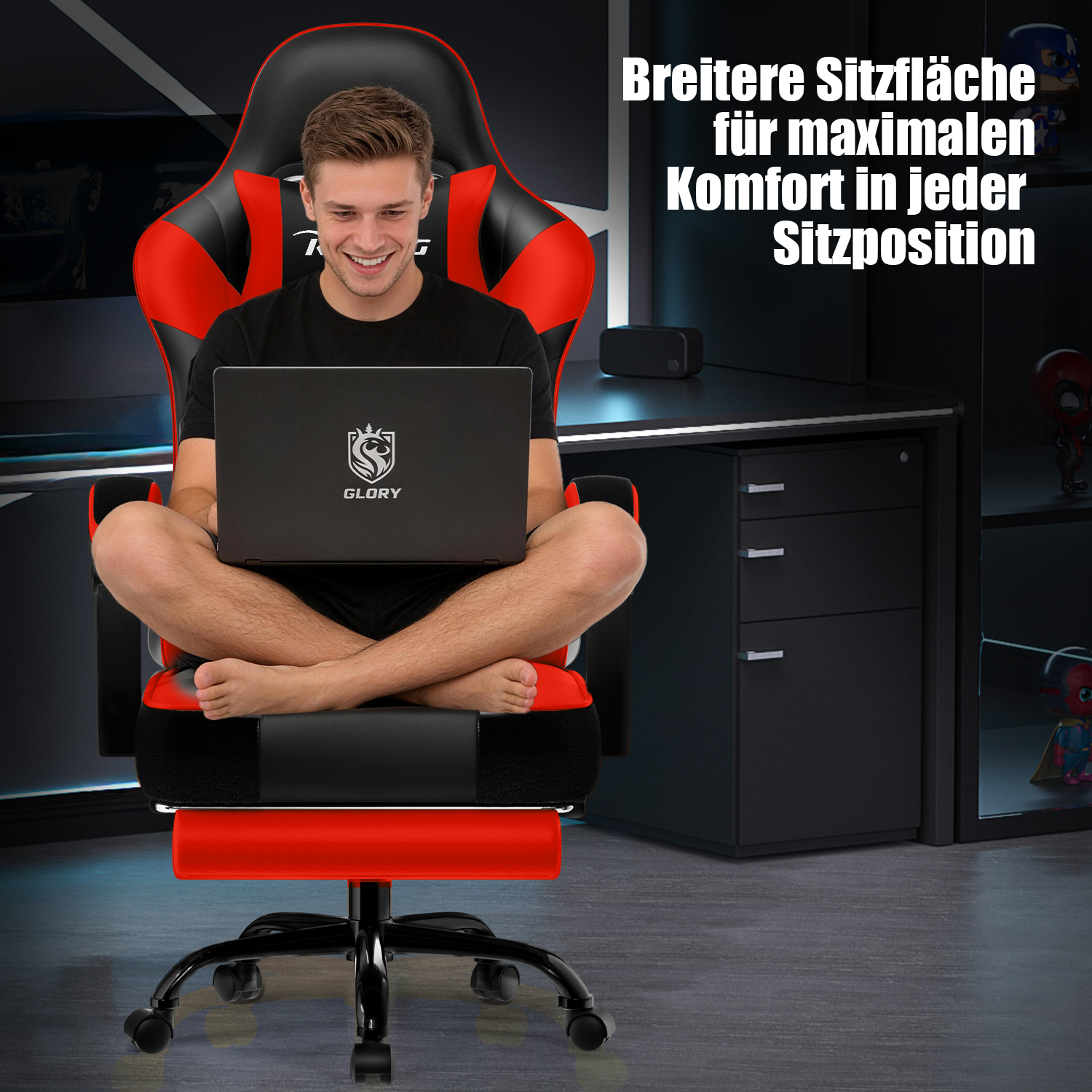 Mann sitzt mit gekreuzten Beinen auf einem rot-schwarzen Gaming-Stuhl und tippt auf einem Laptop.