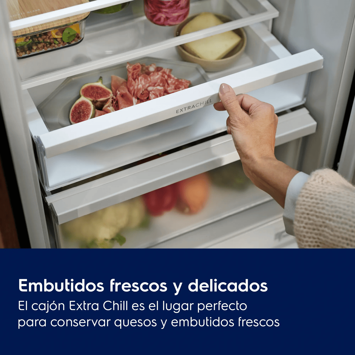Una mano abre el cajón ExtraChill de un frigorífico con embutidos, higos y queso.