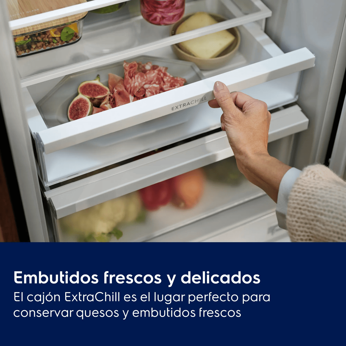 Una mano abre el cajón ExtraChill del frigorífico con higos, embutidos y queso.
