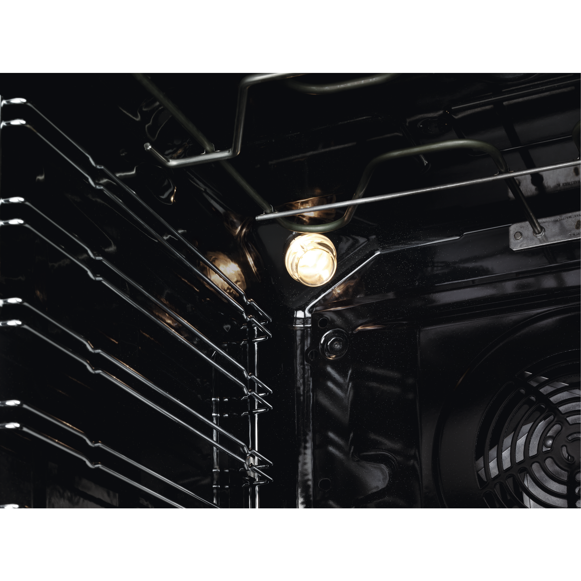 Vista interior de un horno con rejillas brillantes, una bombilla iluminada y el ventilador trasero.