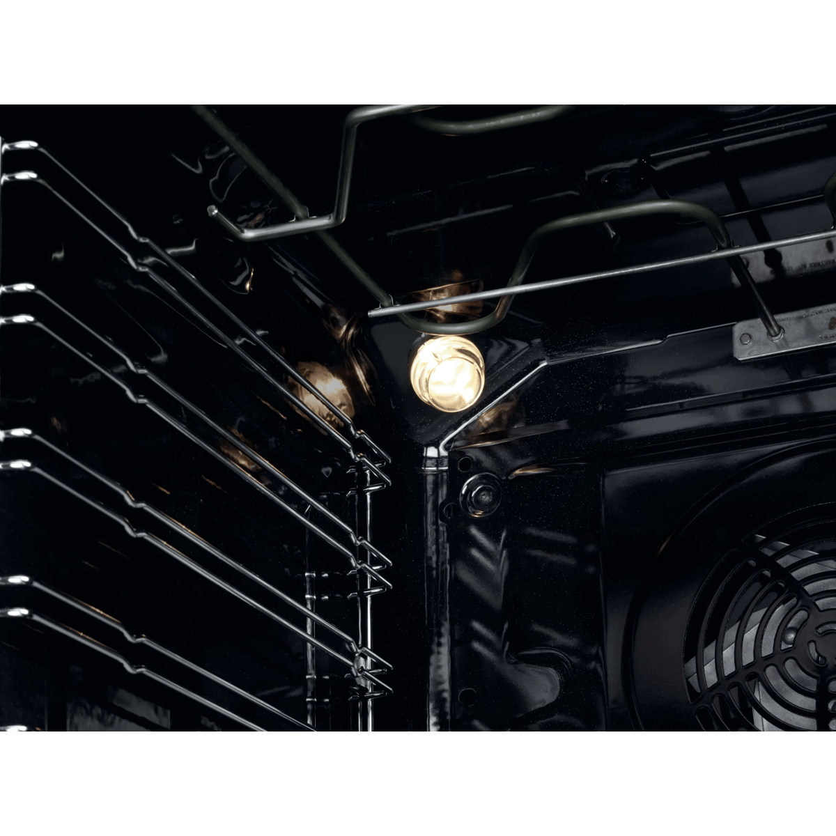 Interior de un horno de metal negro con una bombilla iluminada y rejillas de alambre.