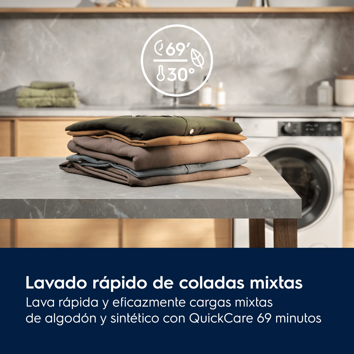 Una pila de ropa doblada sobre una mesa con una lavadora al fondo.
