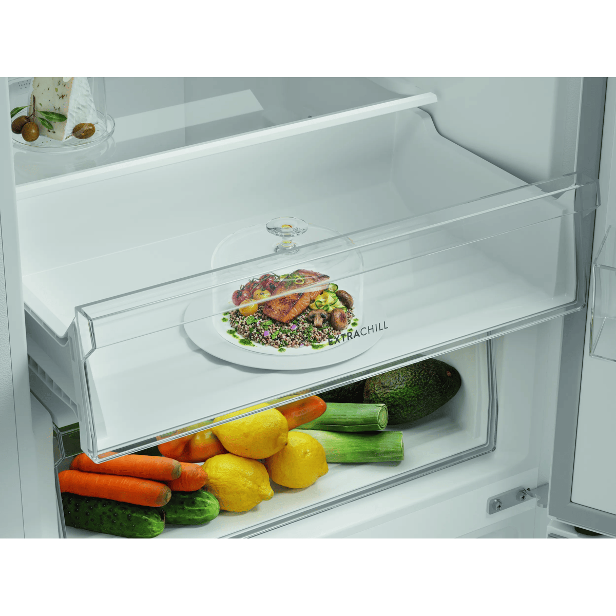 Un refrigerador abierto con un plato de pescado y verduras en un estante y verduras frescas en el cajón inferior.