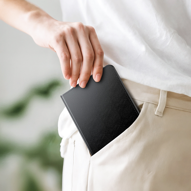 Una persona con camisa blanca guarda un cuaderno negro en el bolsillo de su pantalón.