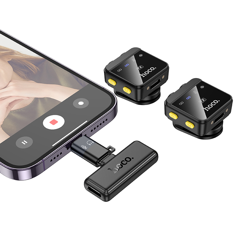 Un smartphone con un receptor inalámbrico conectado y dos pequeños transmisores hoco negros.