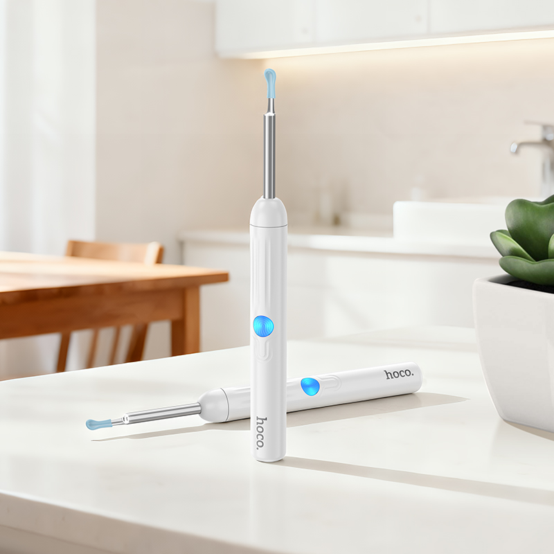Dos limpiadores de oídos eléctricos blancos con accesorios azules sobre una mesa en una cocina.