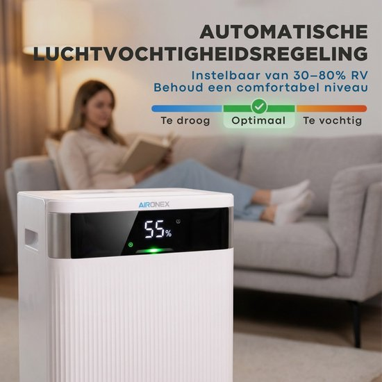 Ein weißer Luftentfeuchter im Vordergrund, während eine Frau im Hintergrund auf einem Sofa liest.