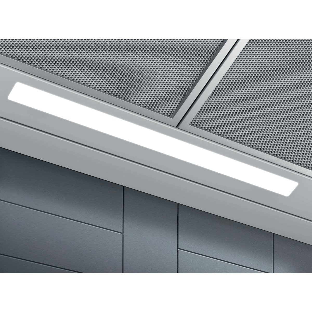 Vista inferior de una campana extractora con tira LED iluminada y rejillas de filtro metálicas ante pared gris.