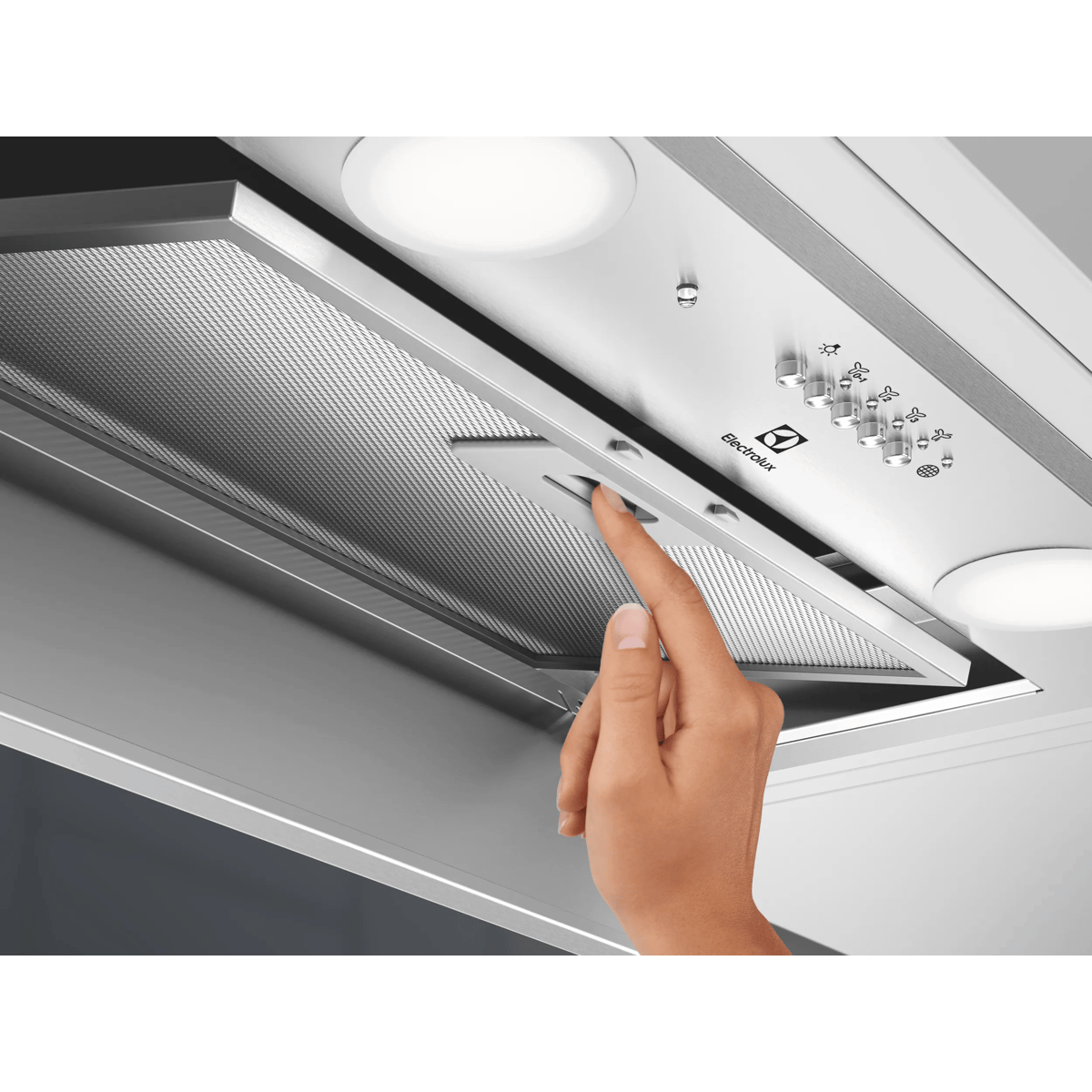 Ręka otwiera metalowy filtr siatkowy okapu kuchennego Electrolux.