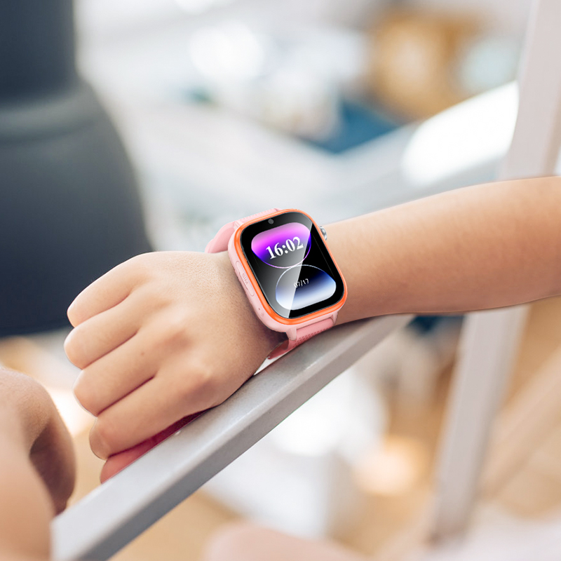 Un niño con un reloj inteligente rosa y naranja con pantalla digital que muestra las 16:02 en un riel blanco.