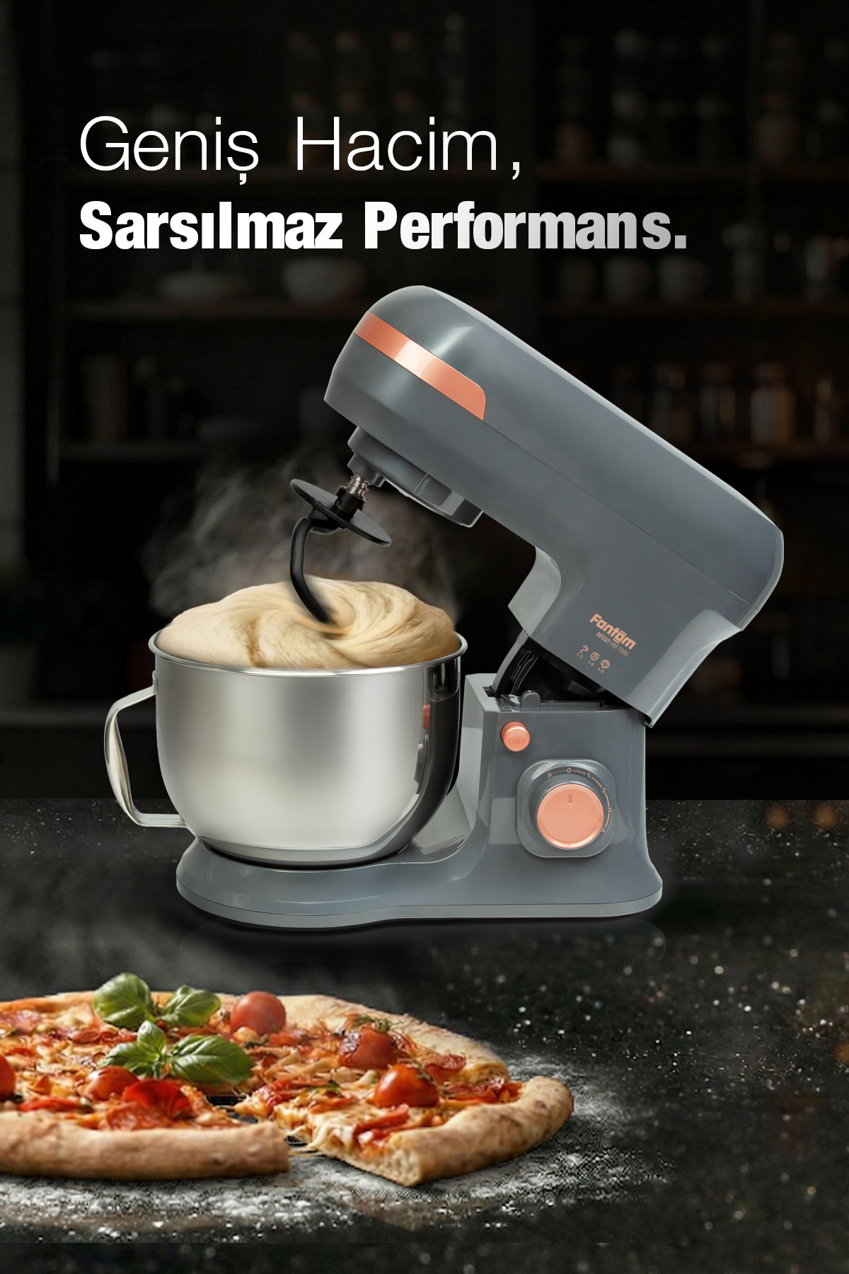 Metal kasesiyle gri mutfak robotu koyu tezgahta hamur yoğuruyor, ön planda pizza var.