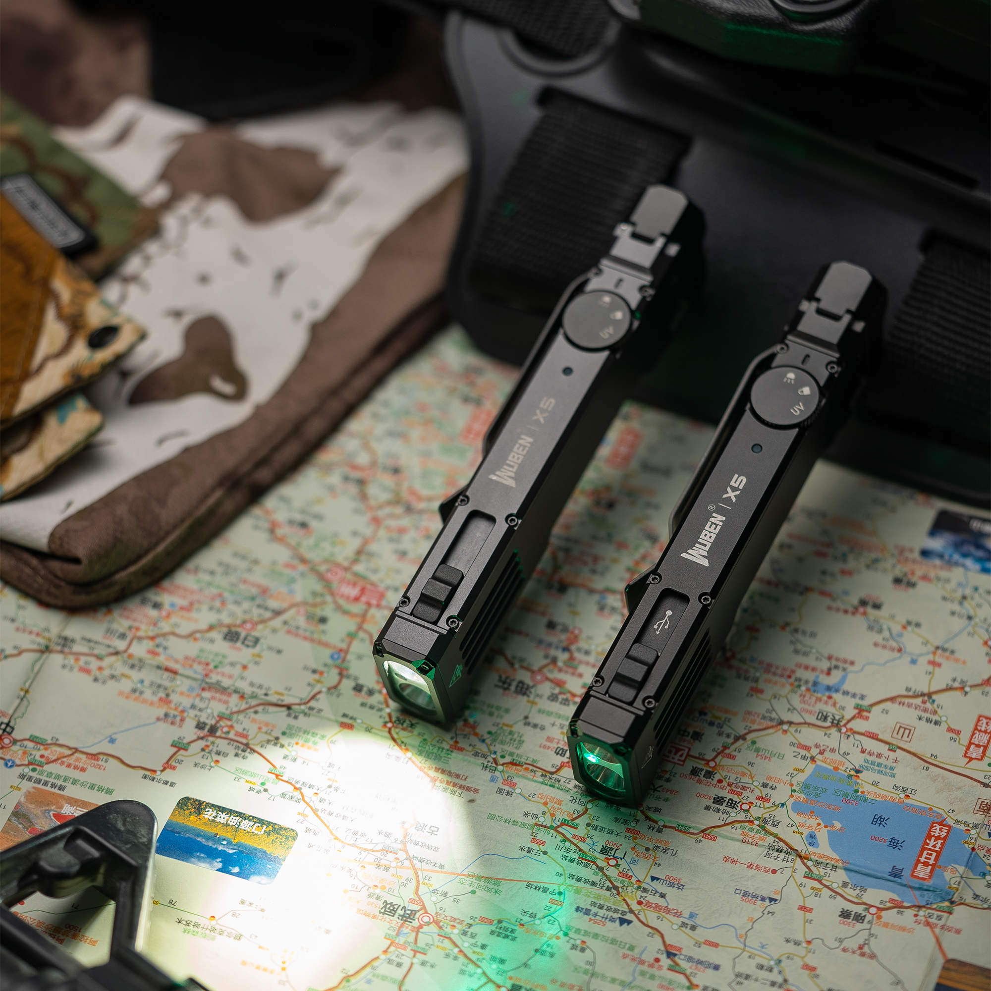 Zwei schwarze taktische Taschenlampen liegen auf einer Karte, eine leuchtet.
