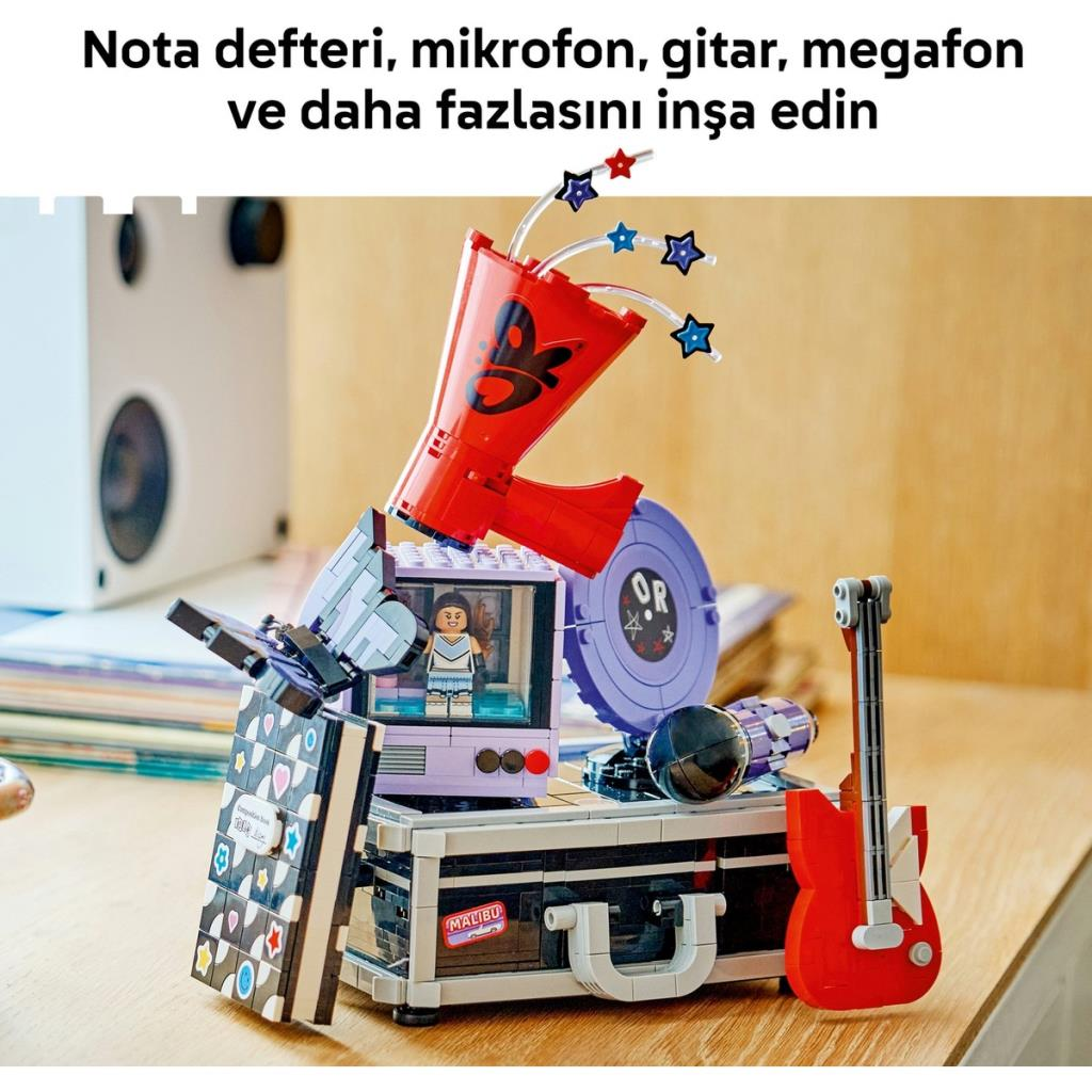Masada kırmızı megafon, mini figürlü mor televizyon, defter, gitar ve hoparlörden oluşan Lego modelleri.