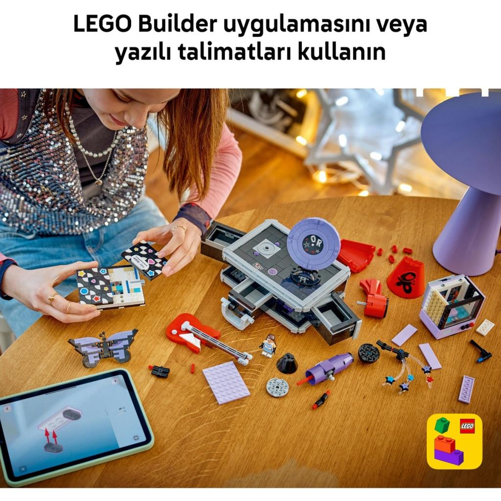 Bir kız, tabletteki dijital talimatları kullanarak ahşap bir masada LEGO yapıyor.