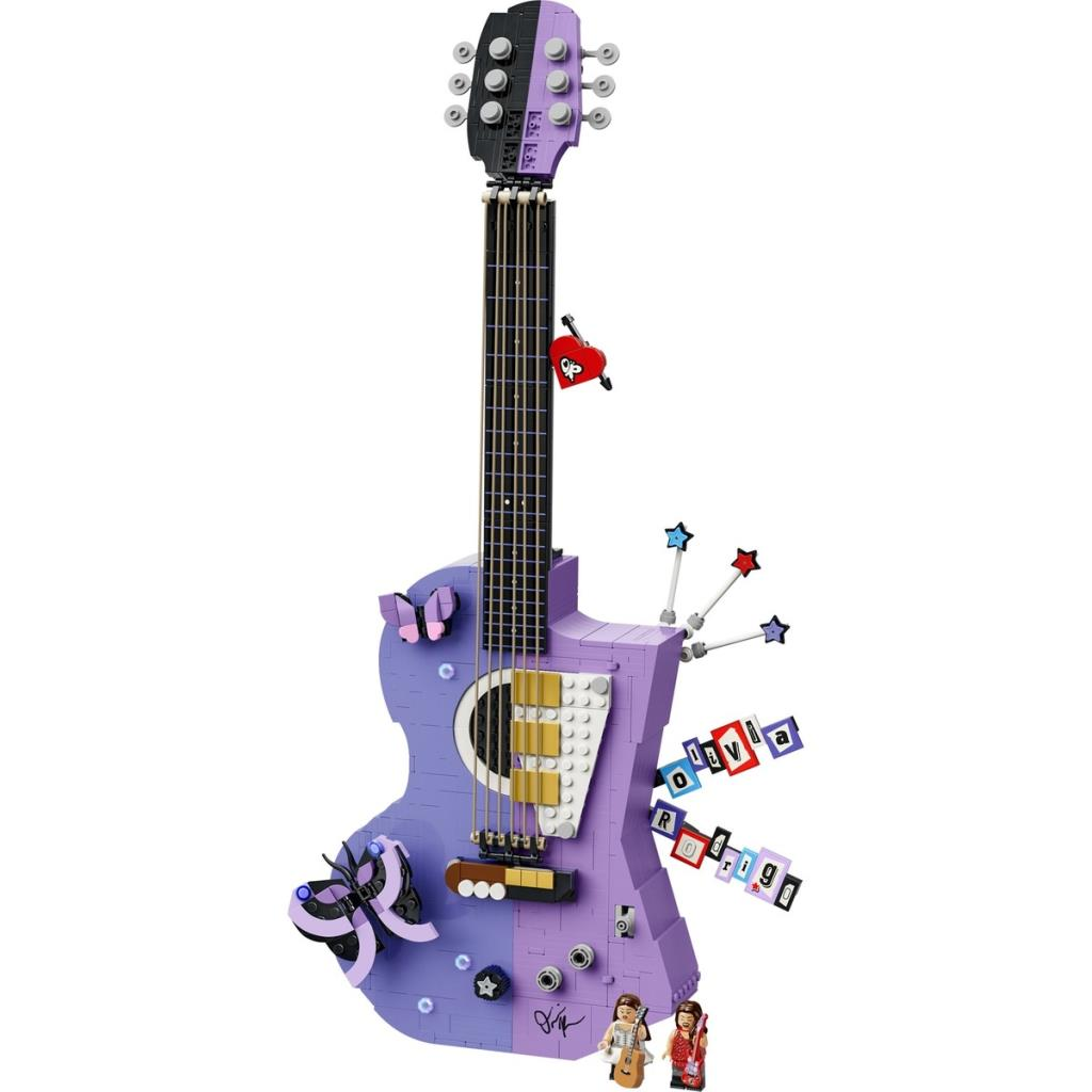 Etiketler, bir kalp, yıldızlar ve altta iki minifigürle süslenmiş özel mor bir Lego gitar modeli.