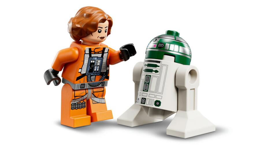 Beyaz arkaplanda turuncu kıyafetli bir kadın pilot Lego figürü ve yanında beyaz-yeşil bir droid.
