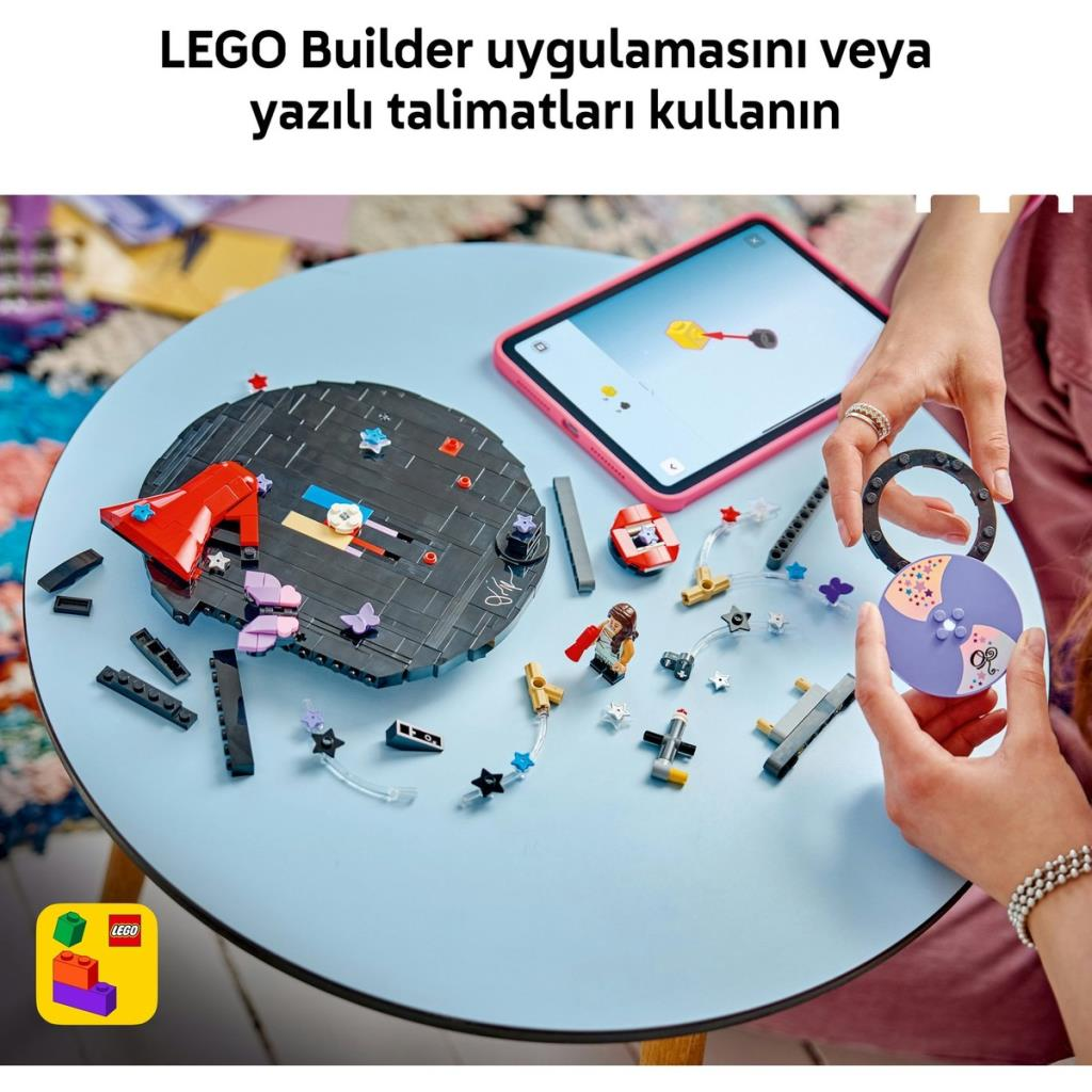Persona che costruisce un set LEGO su un tavolo blu con tablet.