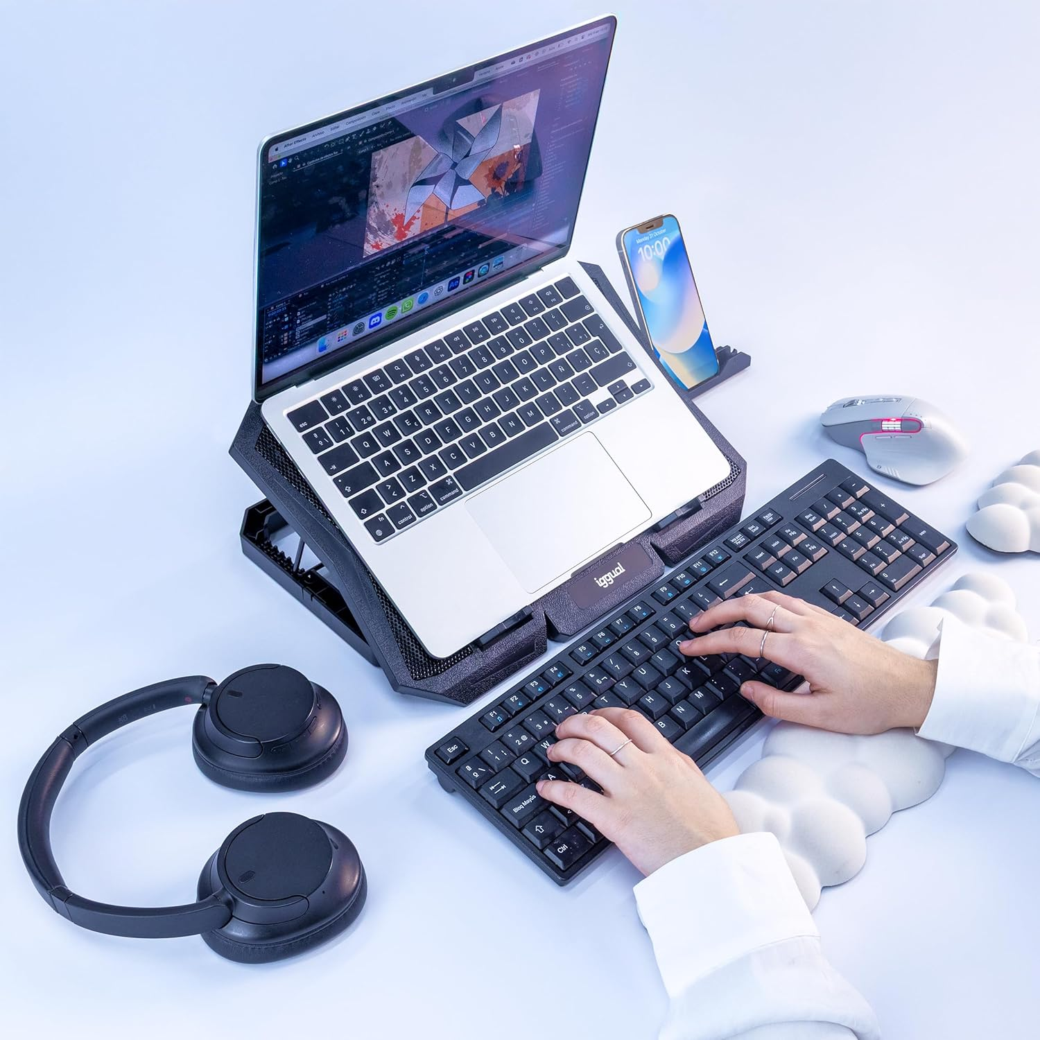 Ein Laptop auf einem Ständer, eine separate Tastatur, Kopfhörer und ein Smartphone auf weißem Untergrund.