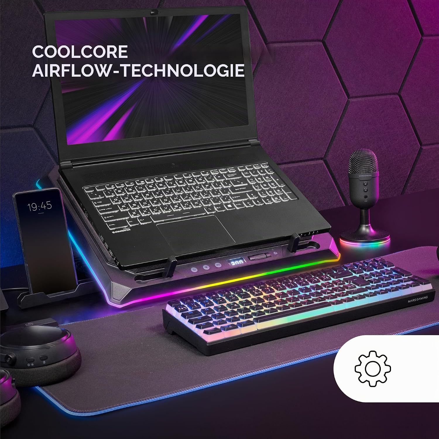 Ein Laptop auf einem RGB-Ständer, eine Tastatur, eine Maus und ein Mikrofon auf einem Schreibtisch vor einer Wand.